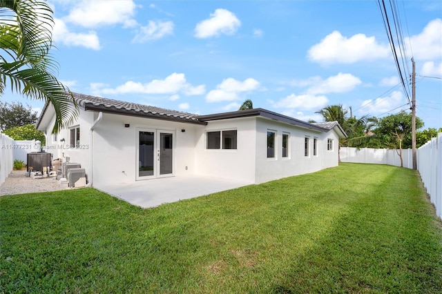 rear view of house with central AC unit, a patio area, and a yard