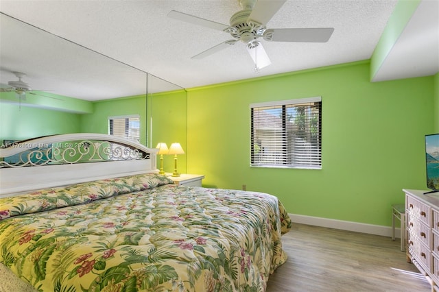 bedroom with light hardwood / wood-style floors, a textured ceiling, and ceiling fan