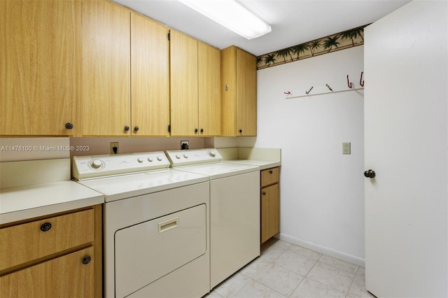 clothes washing area with light tile floors, washer and clothes dryer, and cabinets