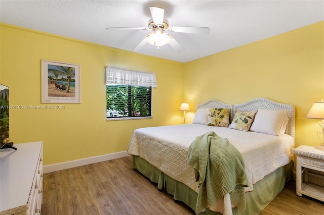 bedroom with light hardwood / wood-style floors, a textured ceiling, and ceiling fan