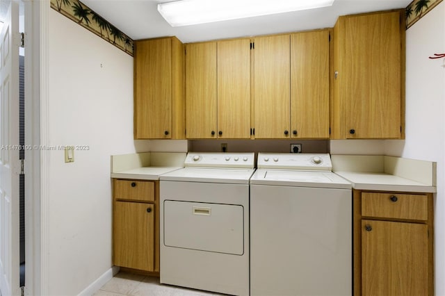 clothes washing area with light tile floors, cabinets, and washer and dryer