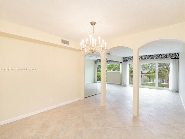 tiled empty room featuring an inviting chandelier