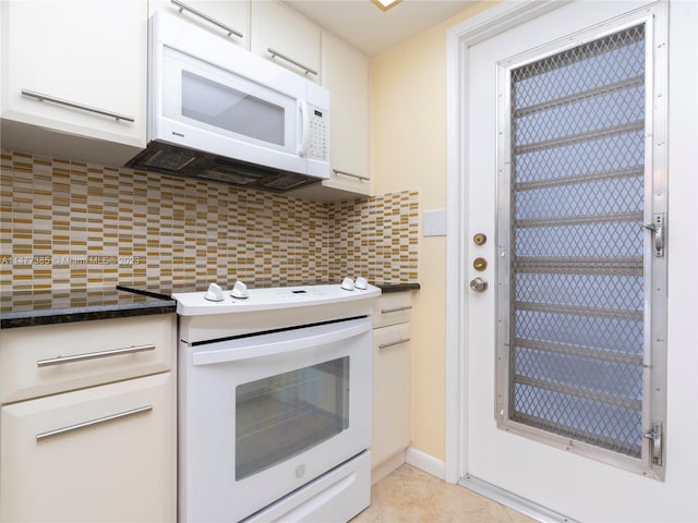 kitchen featuring white appliances, light tile floors, white cabinets, dark stone counters, and tasteful backsplash