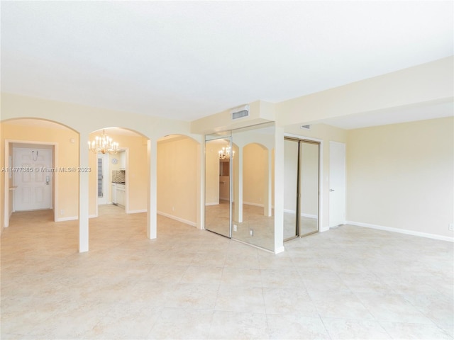 spare room with a chandelier and light tile flooring