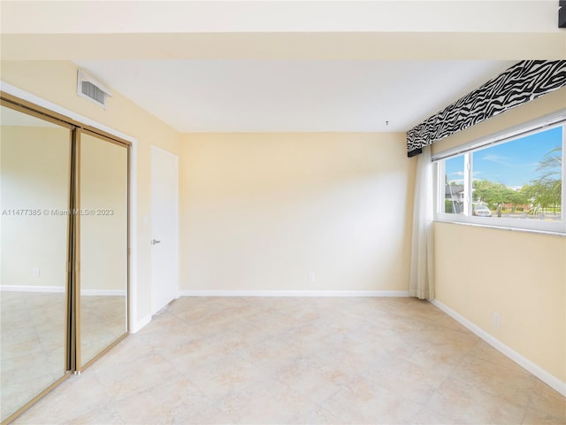 unfurnished bedroom with light tile flooring and a closet