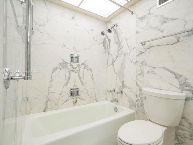 bathroom with tile walls, tiled shower / bath combo, and toilet