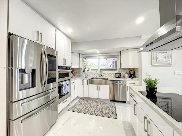 kitchen with stainless steel appliances, wall chimney range hood, light tile flooring, white cabinets, and sink