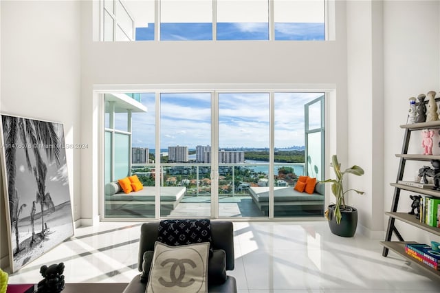 living area featuring a wealth of natural light, tile floors, and a water view