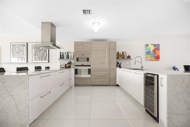 kitchen with wine cooler, sink, wall chimney range hood, and light tile flooring