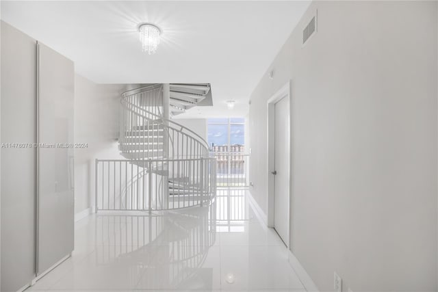 hallway with an inviting chandelier and light tile floors