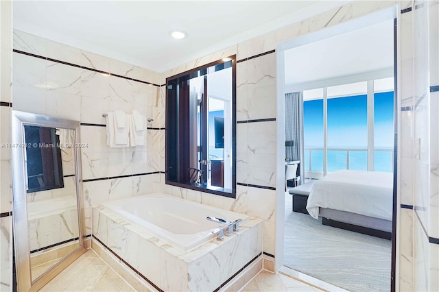 bathroom featuring tile walls, a water view, separate shower and tub, and tile flooring