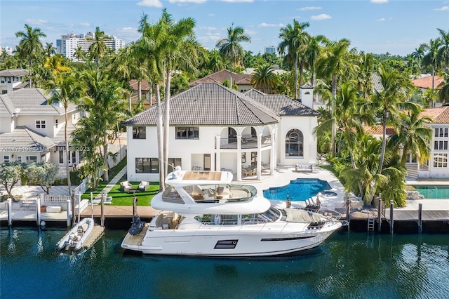 back of property featuring a water view, a patio, a balcony, and stucco siding