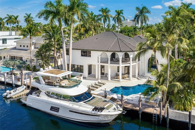 back of house featuring an outdoor pool, a water view, a patio, and a balcony