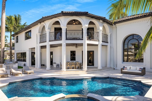 rear view of house with area for grilling, a balcony, a patio area, a pool with connected hot tub, and stucco siding