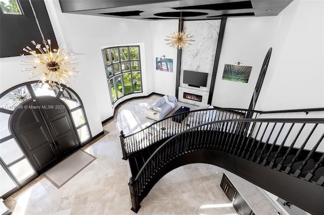 staircase featuring a chandelier, a large fireplace, and baseboards