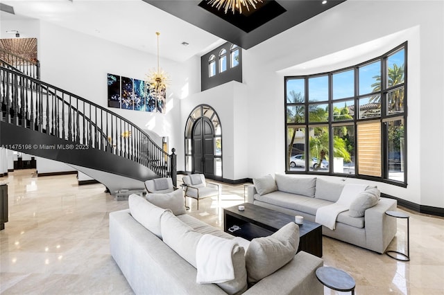 living room featuring marble finish floor, a towering ceiling, stairway, an inviting chandelier, and baseboards