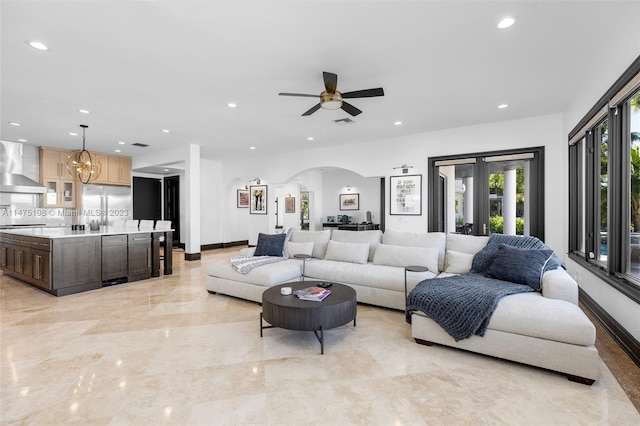 living area featuring marble finish floor, baseboards, arched walkways, and recessed lighting