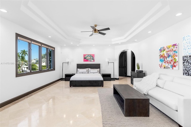 living room featuring baseboards, arched walkways, a ceiling fan, a tray ceiling, and recessed lighting