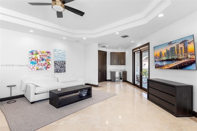 living area with a tray ceiling, recessed lighting, visible vents, and baseboards