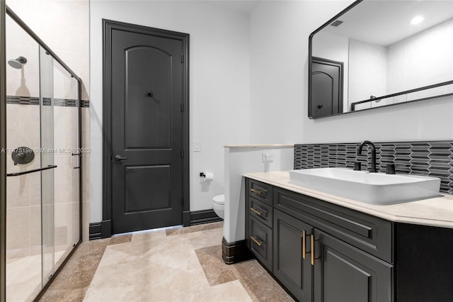 full bathroom featuring a stall shower, baseboards, decorative backsplash, toilet, and vanity