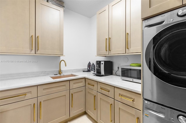 kitchen featuring stacked washer / dryer, stainless steel microwave, a sink, and light stone countertops