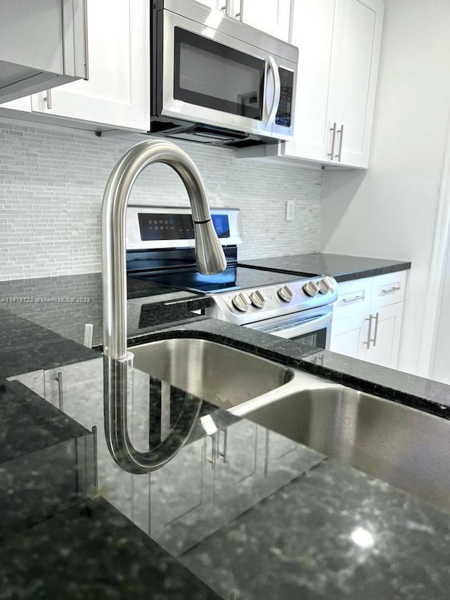 kitchen with decorative backsplash, white cabinets, dark stone counters, and appliances with stainless steel finishes