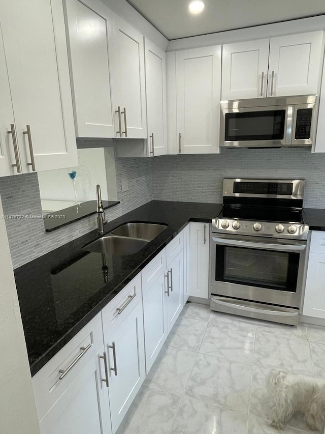 kitchen with sink, dark stone countertops, white cabinetry, and stainless steel appliances