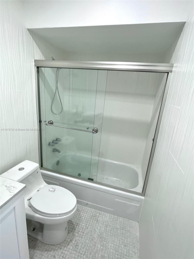 full bathroom with tile patterned floors, vanity, toilet, and bath / shower combo with glass door