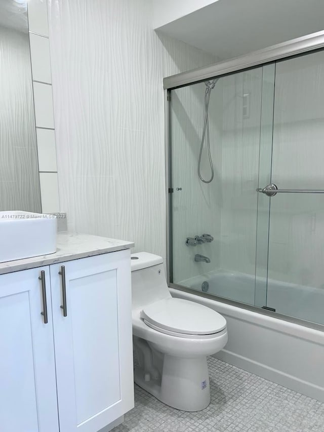 full bathroom with tile patterned floors, vanity, toilet, and bath / shower combo with glass door