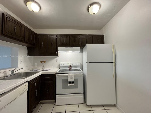 kitchen featuring exhaust hood, dark brown cabinetry, light tile floors, sink, and white appliances