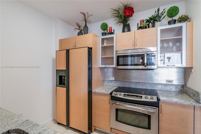 2775 NE 187th St Unit 516, Aventura, FL 33180 - kitchen featuring glass insert cabinets, light brown cabinetry, stainless steel appliances, backsplash, and light tile patterned flooring