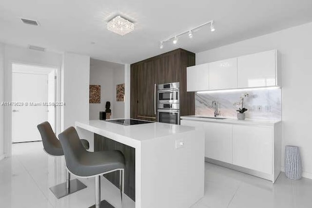 kitchen featuring a kitchen island, light tile flooring, white cabinets, dark brown cabinets, and stainless steel double oven