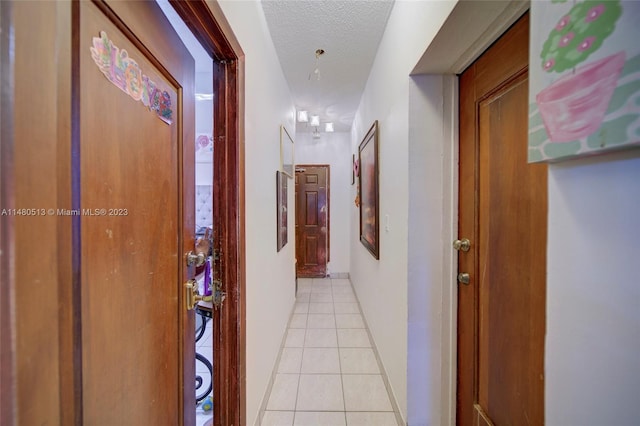 hallway with a textured ceiling and light tile flooring