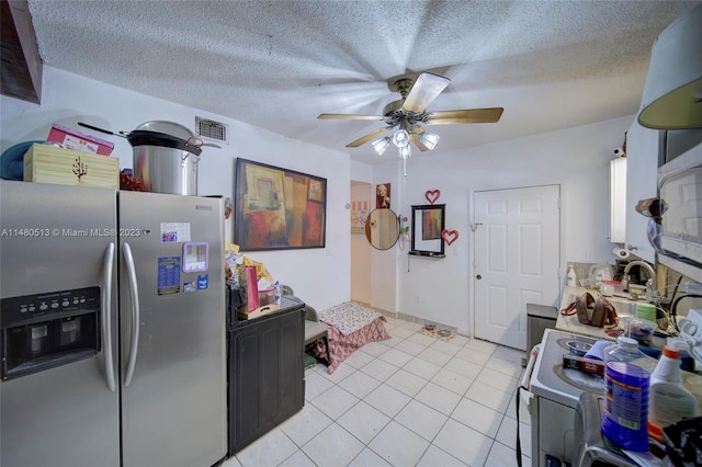 kitchen with light tile floors, ceiling fan, a textured ceiling, range, and stainless steel refrigerator with ice dispenser