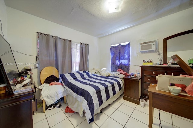 bedroom with a wall mounted AC, light tile floors, and a textured ceiling