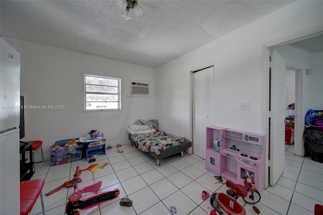 bedroom featuring a wall mounted AC, a closet, light tile floors, and a textured ceiling