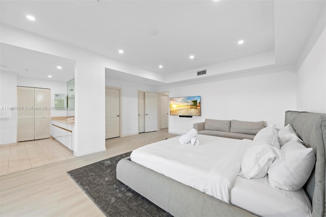 bedroom with connected bathroom and light hardwood / wood-style flooring