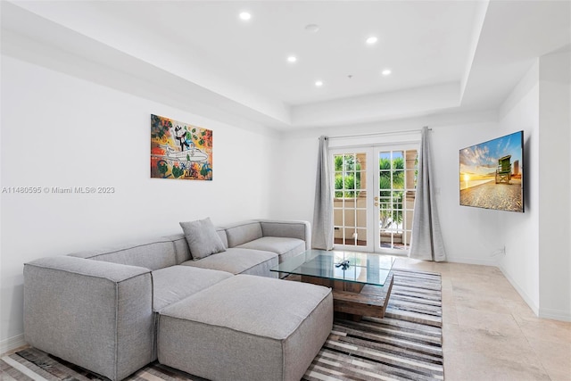 tiled living room featuring french doors and a raised ceiling