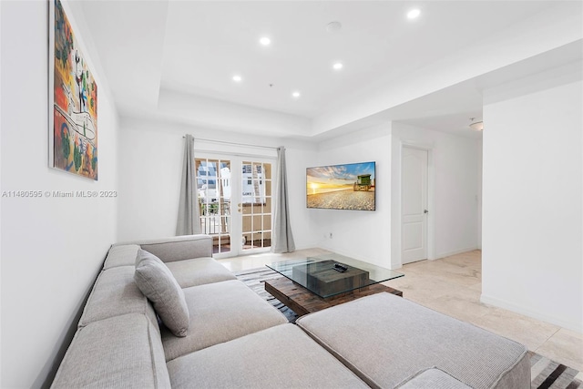 living room featuring light tile floors, a tray ceiling, and french doors