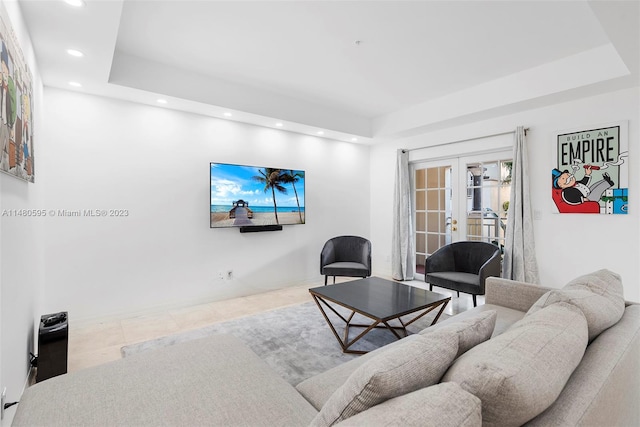 living room with light tile floors, a tray ceiling, and french doors