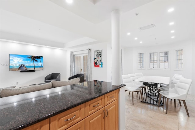 kitchen with dark stone countertops, french doors, light tile floors, and a raised ceiling