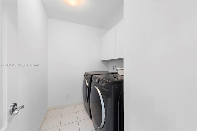 washroom with light tile floors, washer and clothes dryer, and cabinets