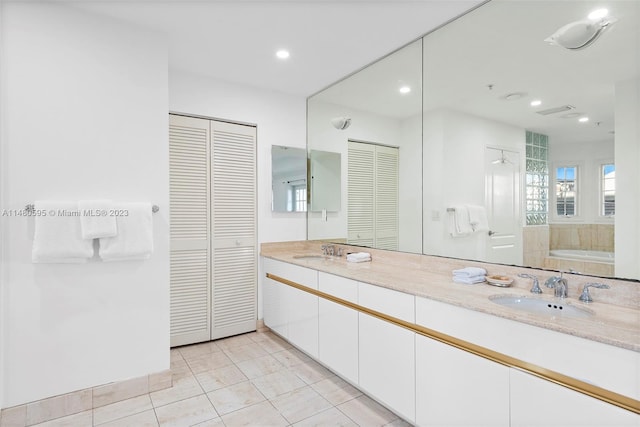 bathroom with tile floors, double sink vanity, and a washtub