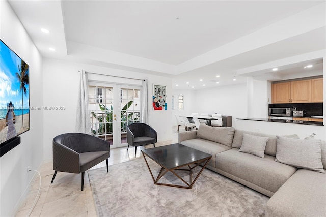 living room with light tile floors, french doors, and a raised ceiling