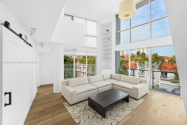 living room featuring a barn door, built in features, and light wood-type flooring