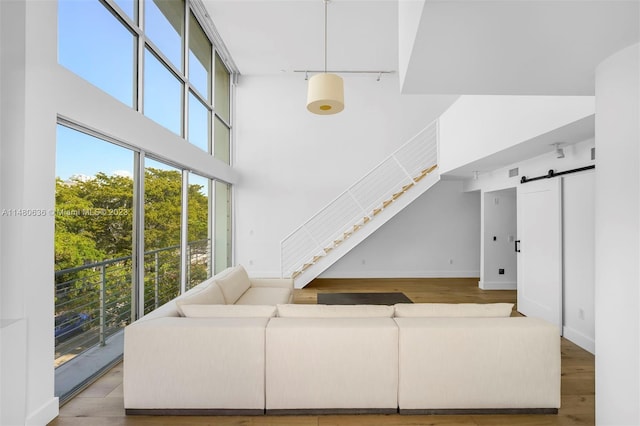 living room featuring a barn door, light hardwood / wood-style floors, and a towering ceiling