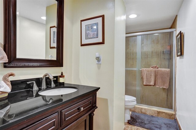 bathroom with vanity, toilet, and a shower with shower door