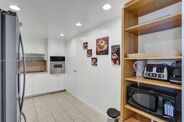 kitchen featuring stainless steel appliances, light tile patterned floors, and white cabinets