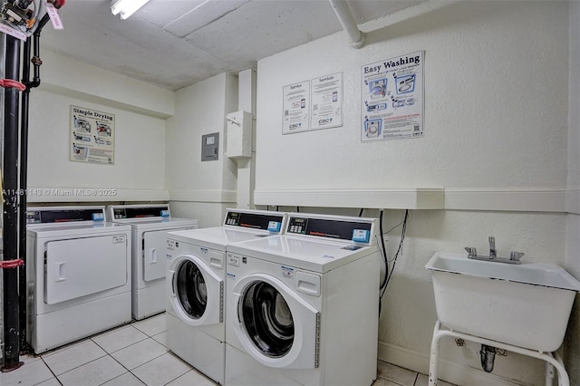 laundry area featuring separate washer and dryer, sink, and light tile patterned floors