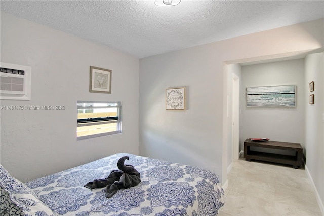 tiled bedroom with a wall unit AC and a textured ceiling